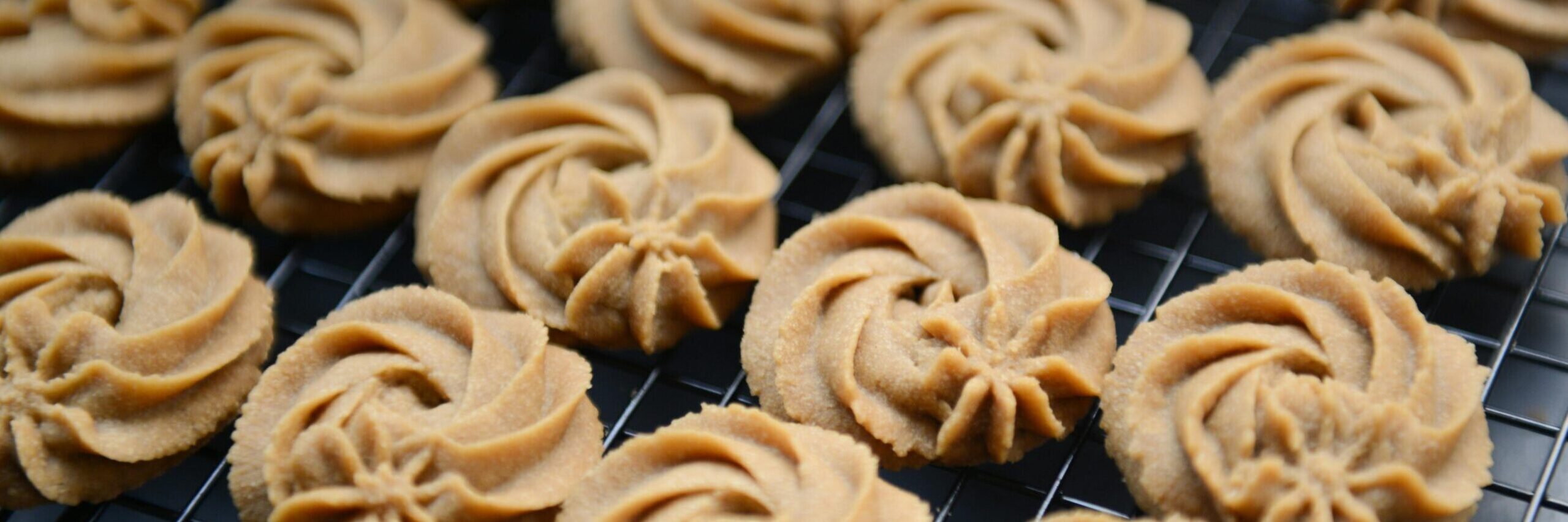 Freshly baked butter cookies arranged on a cooling rack, showcasing their intricate swirls.